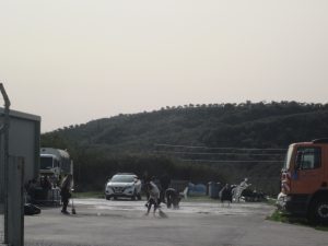 λαθρομετανάστες καθαρίζουν μπροστά από την αποθήκη που φιλοξενούνται.